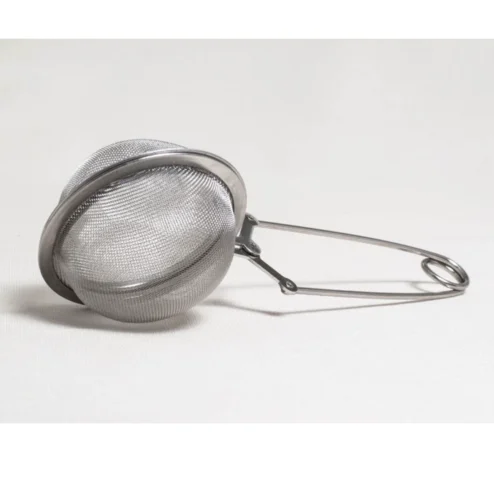 Tetang rustfri stål er en te-infuser i rustfrit stål med net og et håndtag, vist lukket og hvilende på en hvid overflade.